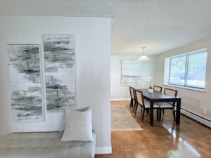 Interior Furnished Model Unit, wood floors, neutral toned walls, abstract art on walls, attached dining room to living room.