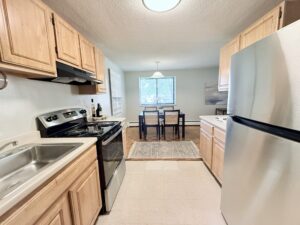 Interior Furnished Unit Kitchen, Laminate floors, Stainless steel appliances, light brown cabinetry, attached dining room to kitchen.